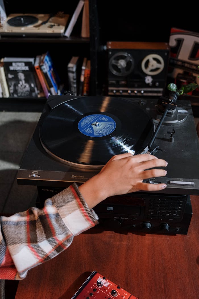 About Close-up of a hand adjusting a vintage vinyl record player in a cozy room setting.